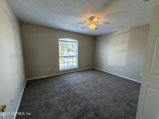 an empty room with windows and chandelier fan