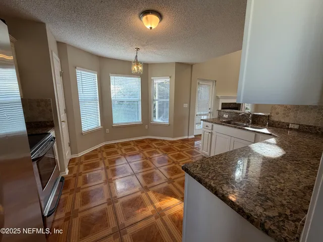 a kitchen with granite countertop a sink a counter top space and cabinets