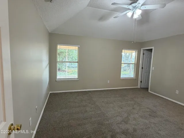 an empty room with windows and fan