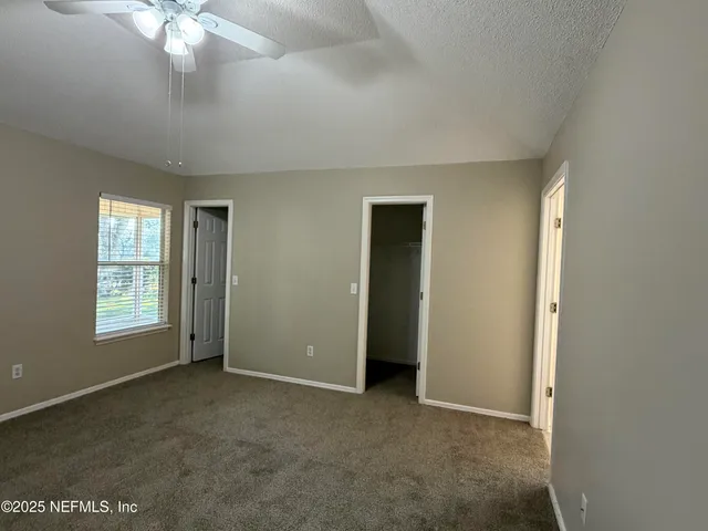an empty room with chandelier fan and windows