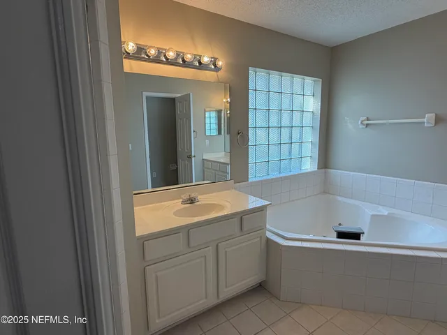 a bathroom with a tub sink and mirror