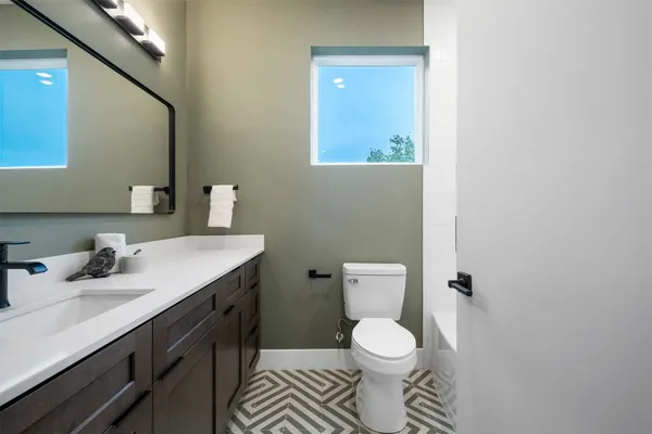 a bathroom with a granite countertop toilet sink and mirror
