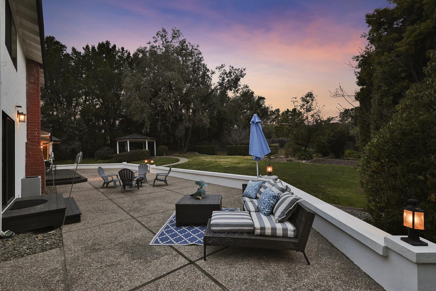 20 Tea Tree Court Hillsborough, CA 94010 - Photo 14 of 100 a view of a patio with couches table and chairs under an umbrella with large trees