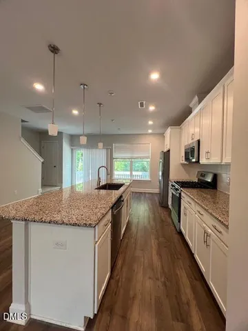 a kitchen with stainless steel appliances granite countertop a refrigerator a sink a stove and a microwave