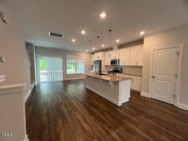 a kitchen with stainless steel appliances granite countertop a stove a sink and a refrigerator