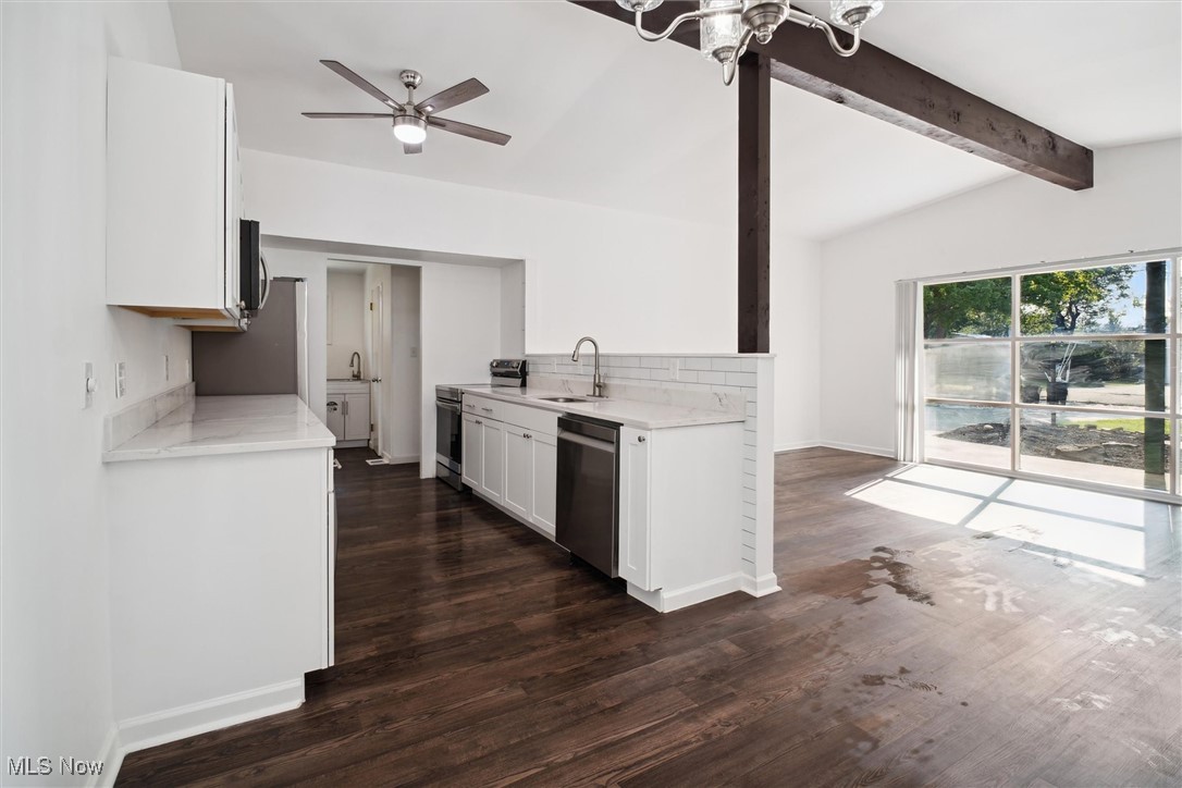 6683 Sherborn Road Cleveland, OH 44130 - Photo 10 of 42 Kitchen featuring dark wood-type flooring, ceiling fan with notable chandelier, sink, stainless steel appliances, and lofted ceiling with beams
