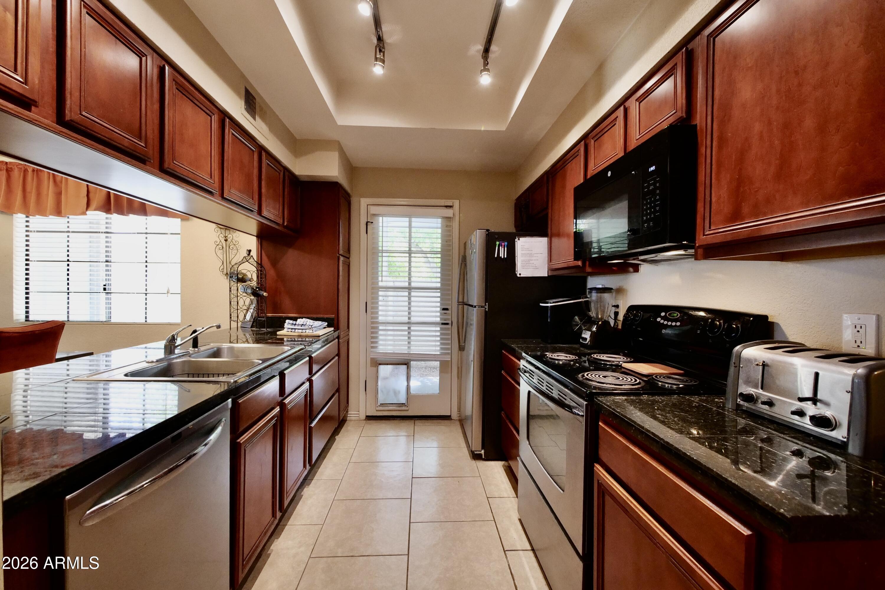 1222 West Baseline Road, Unit 156 Tempe, AZ 85283 - Photo 12 of 27 a kitchen with stainless steel appliances granite countertop a stove top oven a sink dishwasher and a refrigerator