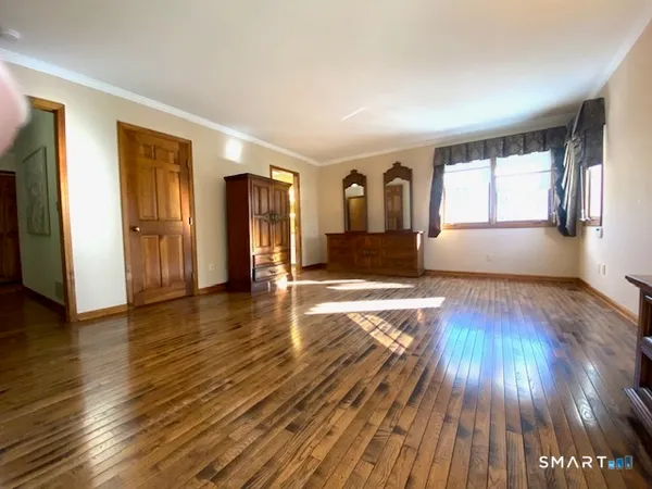 a view of empty room with wooden floor and window