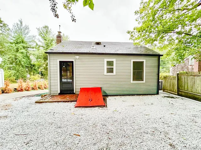 a backyard of a house with wooden fence and a tree