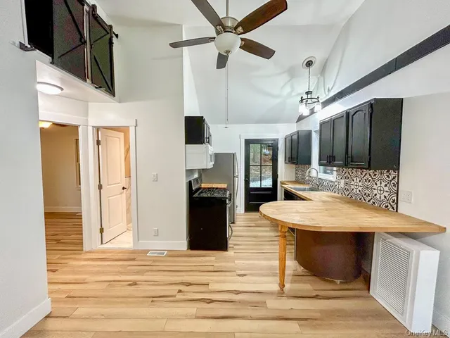 a kitchen with stainless steel appliances kitchen island granite countertop a refrigerator a stove and a sink with wooden floor