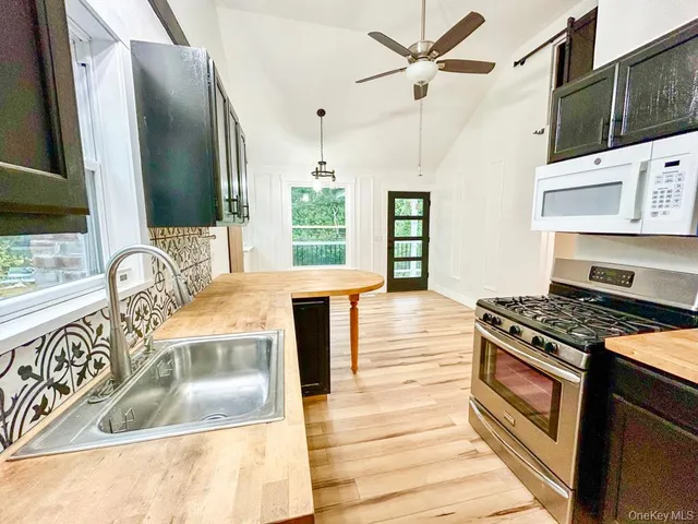 a kitchen with stainless steel appliances granite countertop a stove a sink and a microwave