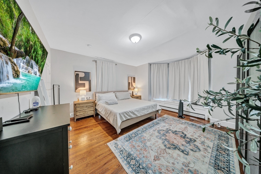 28 Richards Street Worcester, MA 01603 - Photo 13 of 42 a spacious bedroom with a bed a table and a flat screen tv