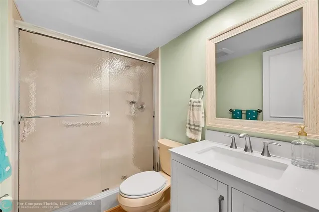 a bathroom with a sink a mirror a toilet and shower