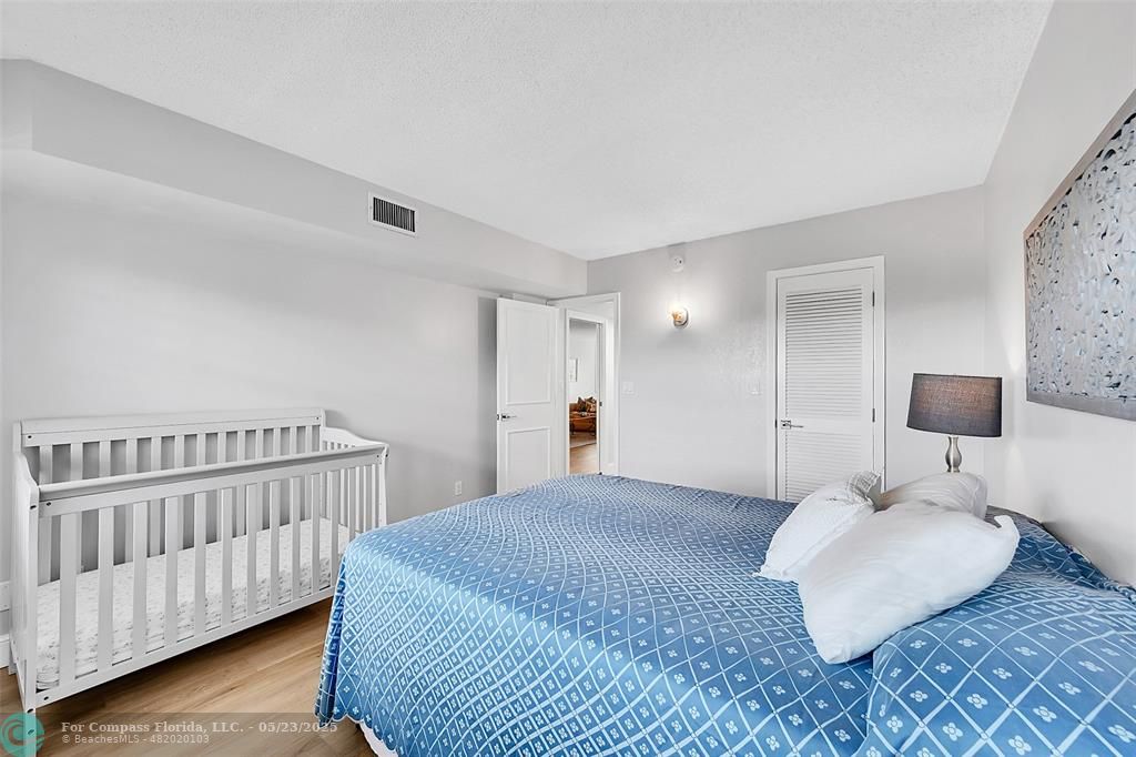 4020 West Palm Aire Drive, Unit 503 Pompano Beach, FL 33069 - Photo 28 of 53 a bedroom with a bed and a lamp with the wooden floor