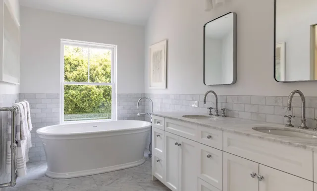 a bathroom with a bathtub a sink a window and a mirror