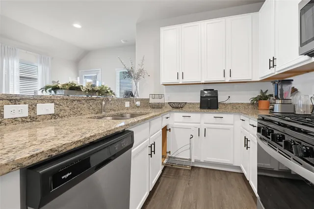 a kitchen with granite countertop white cabinets and white appliances