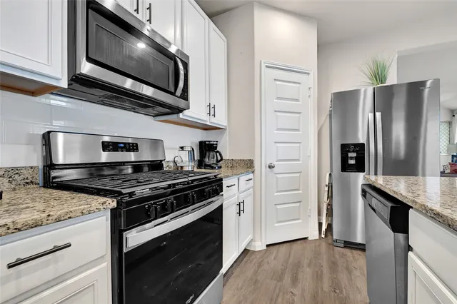 a kitchen with stainless steel appliances granite countertop a stove microwave and refrigerator