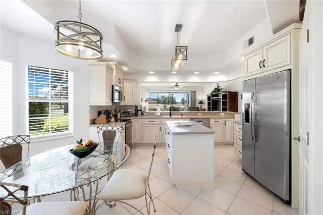 a kitchen with stainless steel appliances kitchen island granite countertop a refrigerator a oven a sink a dining table and chairs with wooden floor