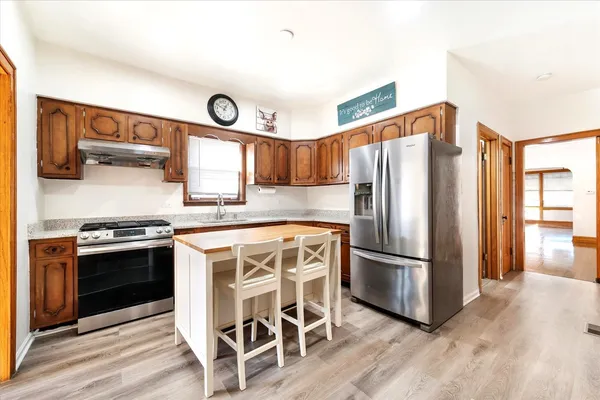 a kitchen with stainless steel appliances granite countertop a stove a refrigerator and a refrigerator with wooden floors