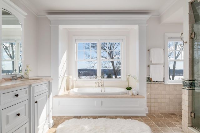 a spacious bathroom with a tub sink and large window