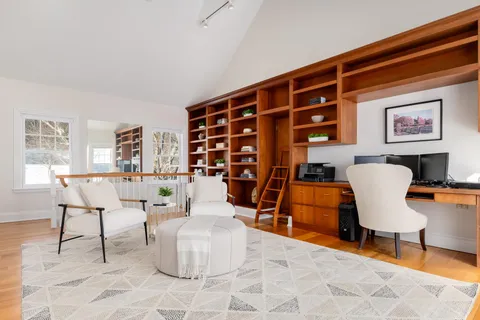 a living room with furniture a lamp and a large window with potted plants