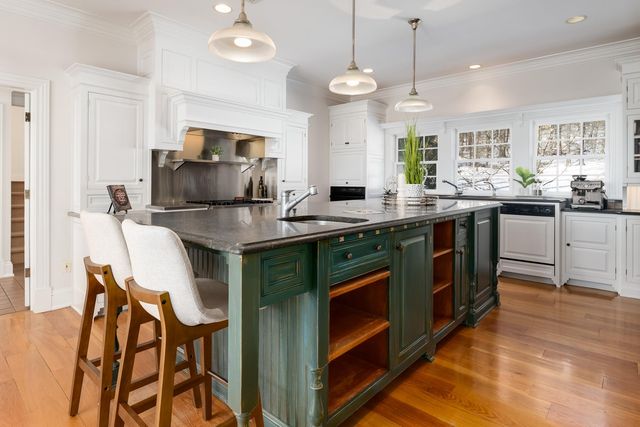a kitchen with kitchen island granite countertop a sink counter and chairs