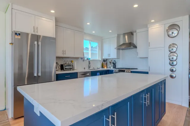 a kitchen with stainless steel appliances granite countertop a sink a stove a refrigerator and a refrigerator