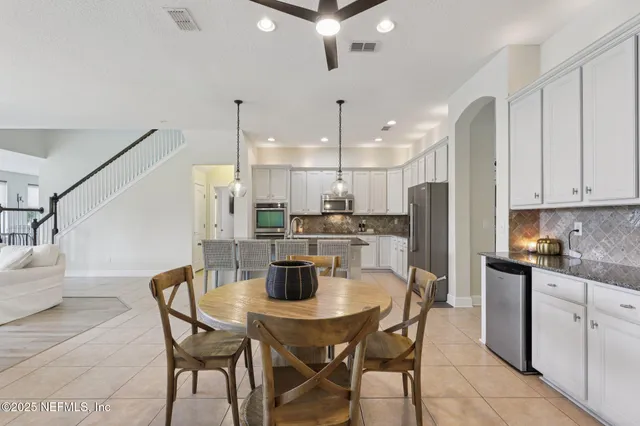 a kitchen with stainless steel appliances kitchen island granite countertop a table chairs and a refrigerator