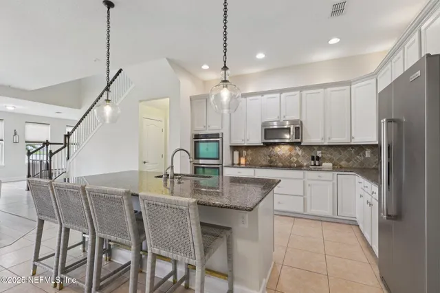 a kitchen with kitchen island granite countertop a table chairs refrigerator and microwave