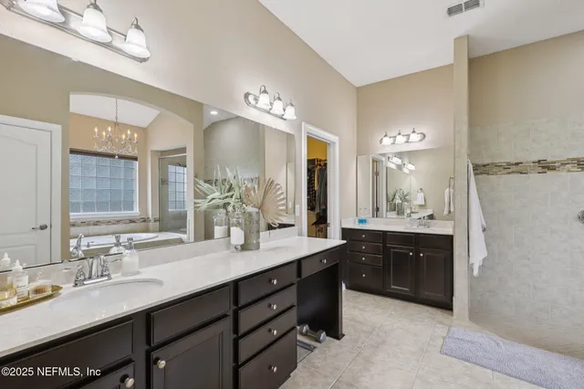 a bathroom with a tub a sink double vanity and a mirror