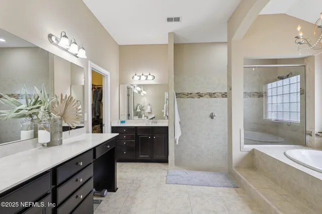 a spacious bathroom with a granite countertop sink a mirror a bathtub and shower