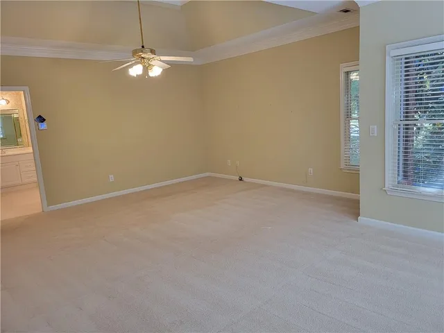 an empty room with a chandelier fan and a window
