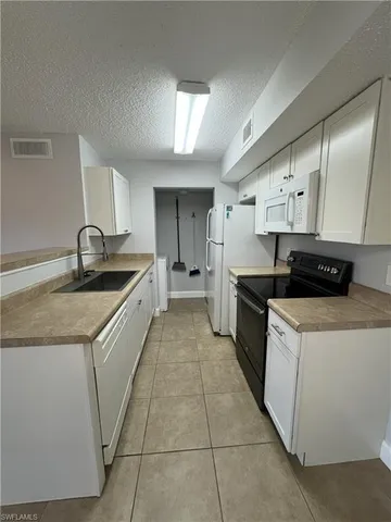 a kitchen with granite countertop a sink and white cabinets