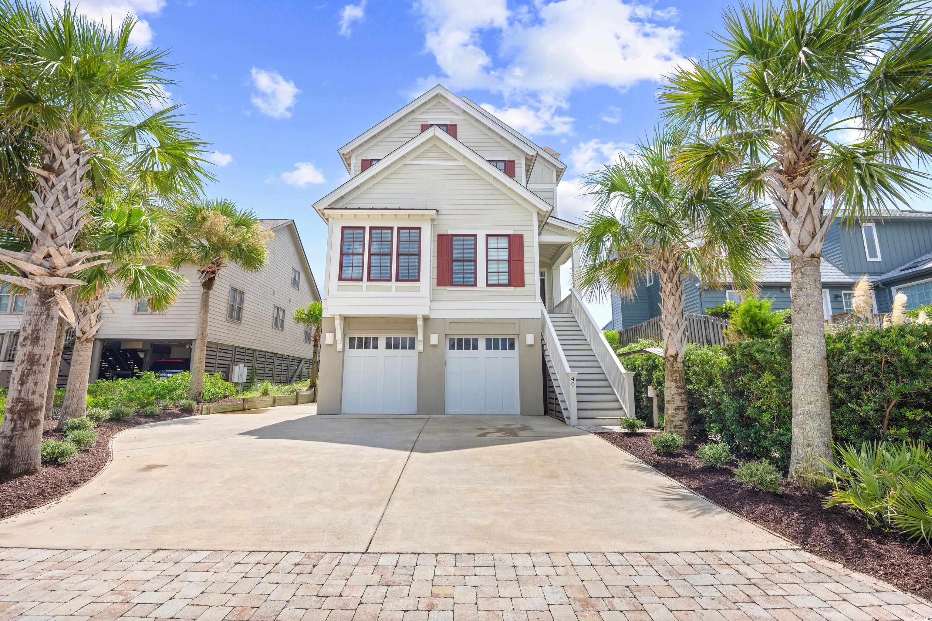 Beach home with driveway, a garage, stairs, and a balcony