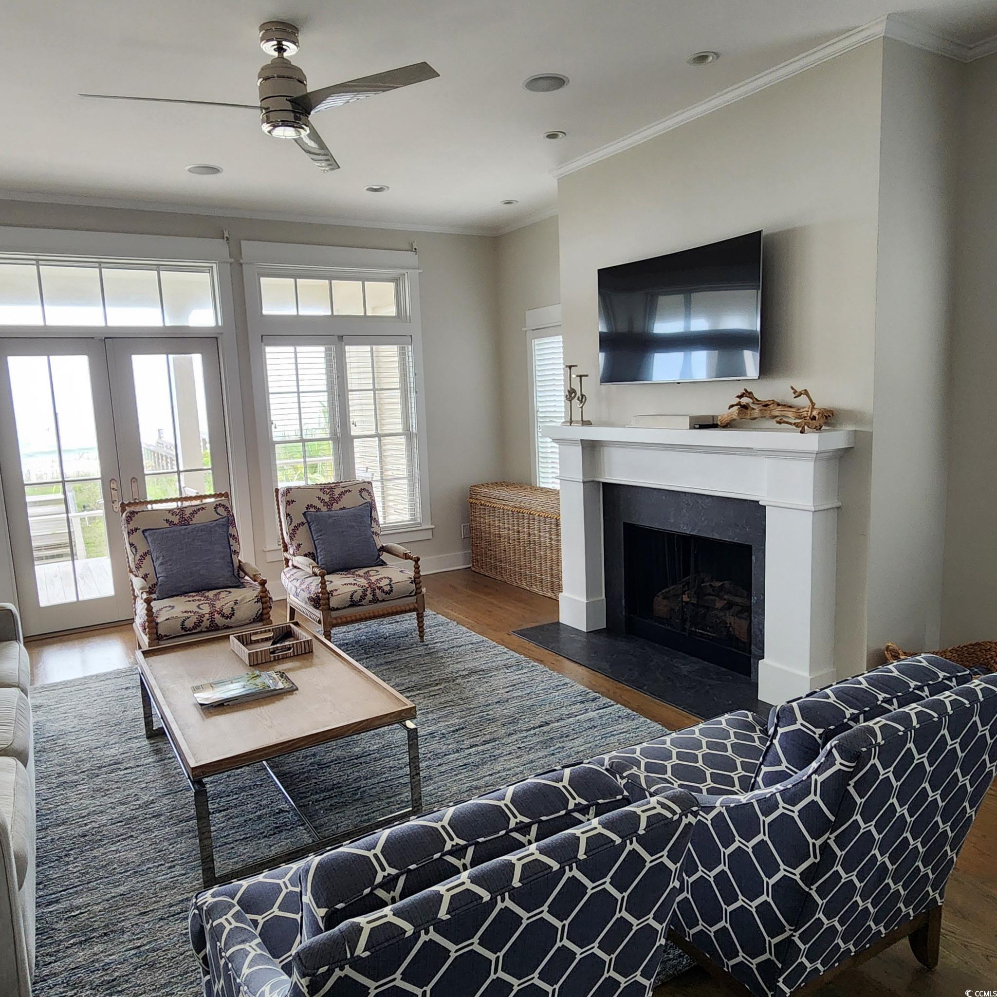 40 Seaview Loop Pawleys Island, SC 29585 - Photo 13 of 34 Living room featuring dark wood-type flooring, ornamental molding, plenty of natural light, a fireplace with flush hearth, and a ceiling fan