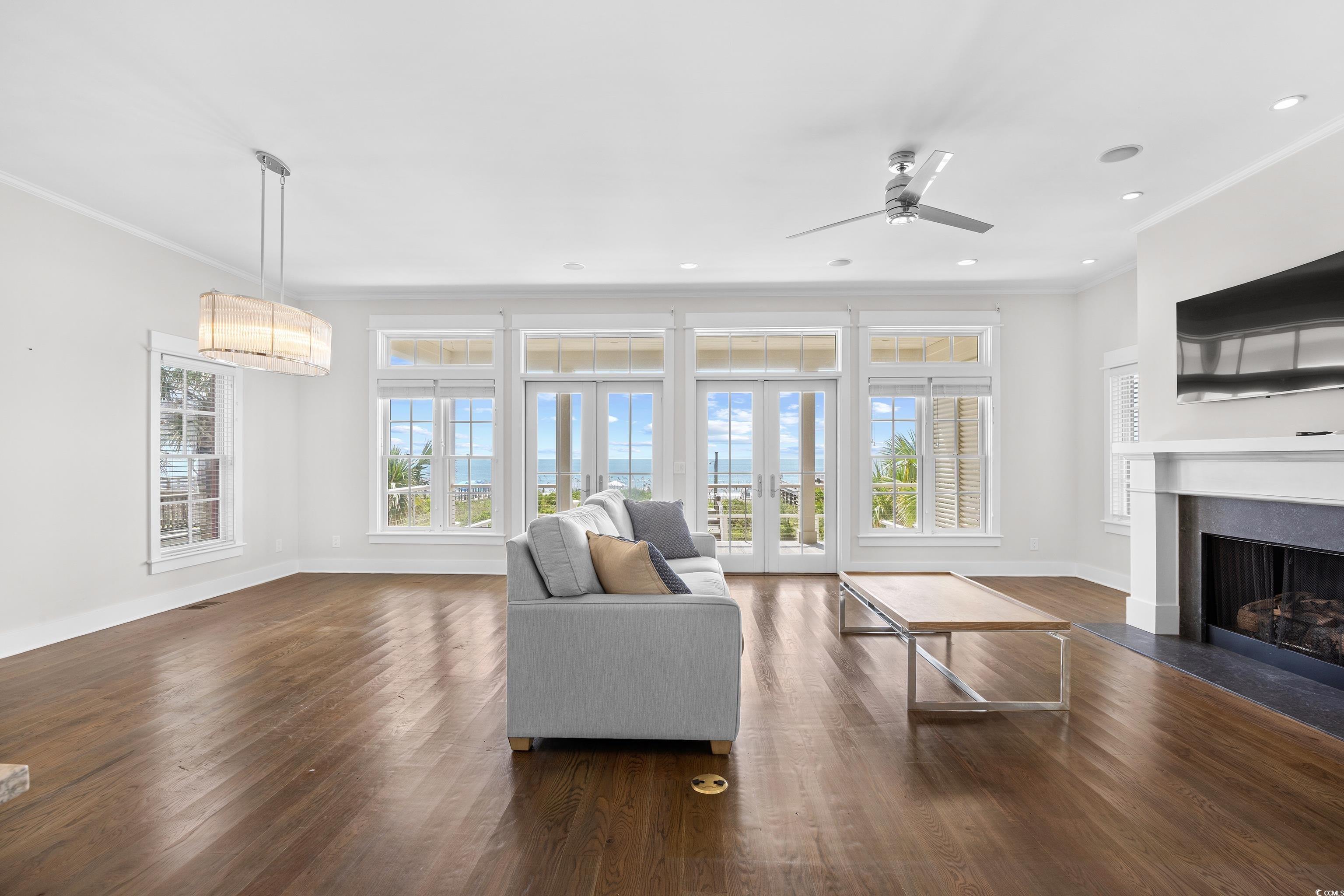 40 Seaview Loop Pawleys Island, SC 29585 - Photo 10 of 34 Living area featuring crown molding, healthy amount of natural light, a fireplace with flush hearth, dark wood finished floors, and french doors