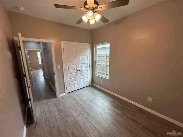 an empty room with wooden floor and fan