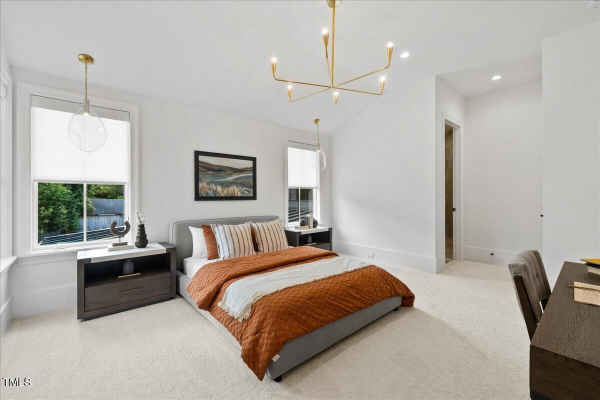 222 Reynolds Road Raleigh, NC 27609 - Photo 32 of 43 a bedroom with a large bed and a chandelier