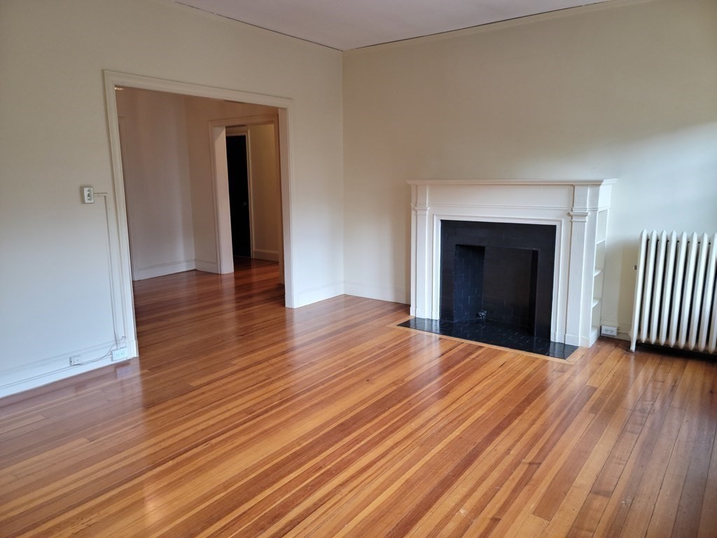 7 Lewis Road, Unit 2 Winchester, MA 01890 - Photo 2 of 13 an empty room with wooden floor fireplace and windows