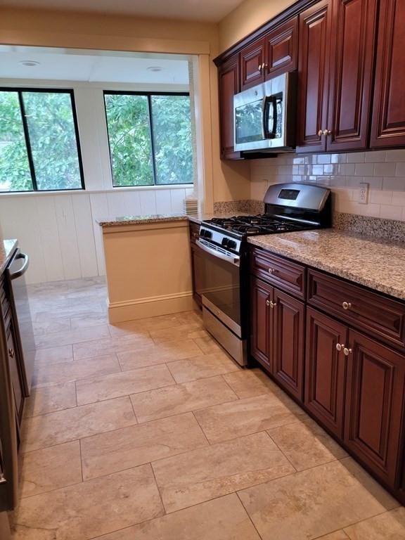 7 Lewis Road, Unit 2 Winchester, MA 01890 - Photo 3 of 13 a kitchen with stainless steel appliances granite countertop a stove a sink and a microwave