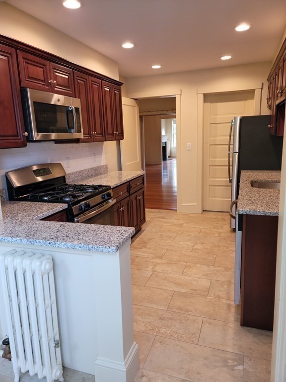 7 Lewis Road, Unit 2 Winchester, MA 01890 - Photo 4 of 13 a kitchen with stainless steel appliances granite countertop a stove a sink and a microwave