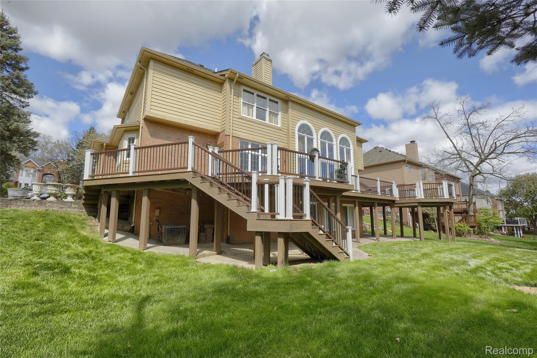 2007 Mapleridge Road Rochester, MI 48309 - Photo 42 of 45 Back of property featuring a wooden deck, a chimney, a lawn, and a patio area