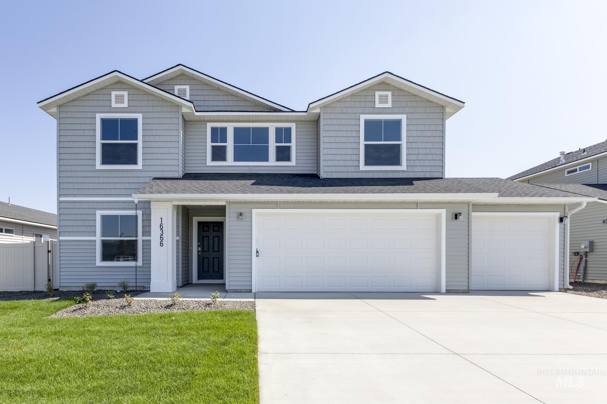 View of front of home with driveway and a shingled roof