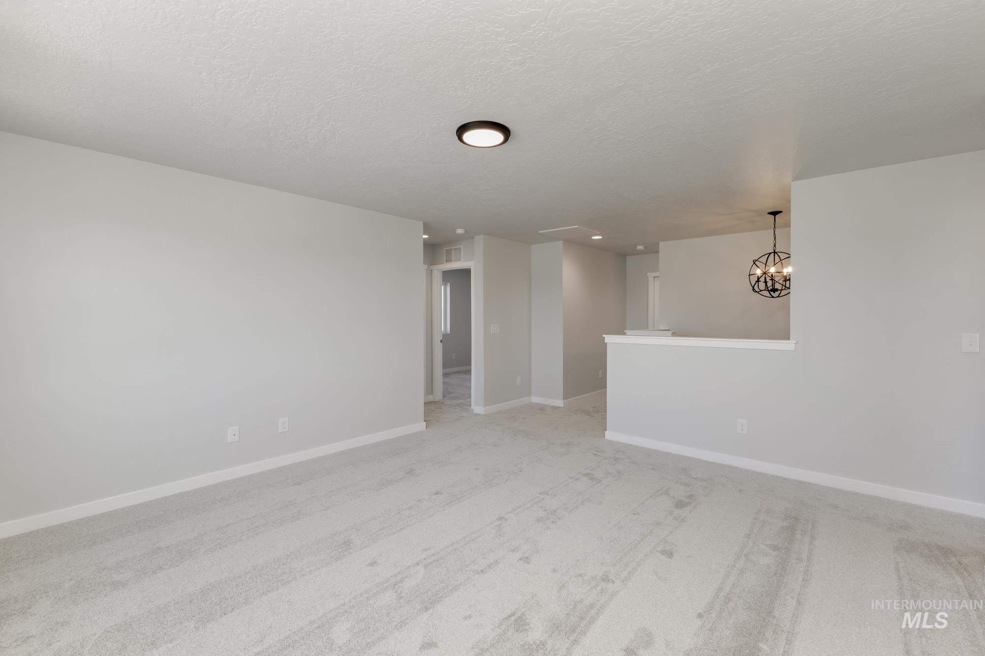 16366 Backfill Avenue Caldwell, ID 83607 - Photo 14 of 24 Unfurnished room with light colored carpet, a textured ceiling, and a chandelier