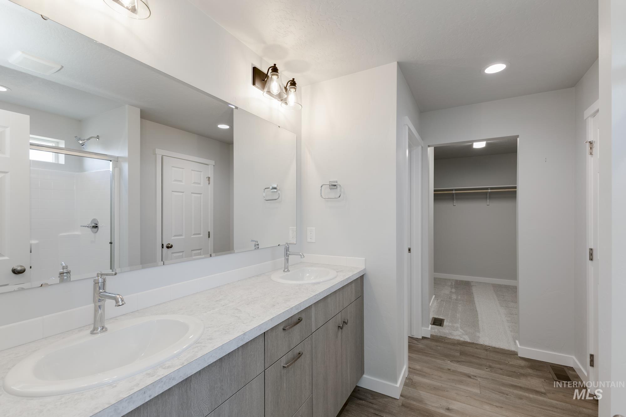 16366 Backfill Avenue Caldwell, ID 83607 - Photo 23 of 24 Bathroom with recessed lighting, double vanity, a walk in closet, light wood-style floors, and a shower stall