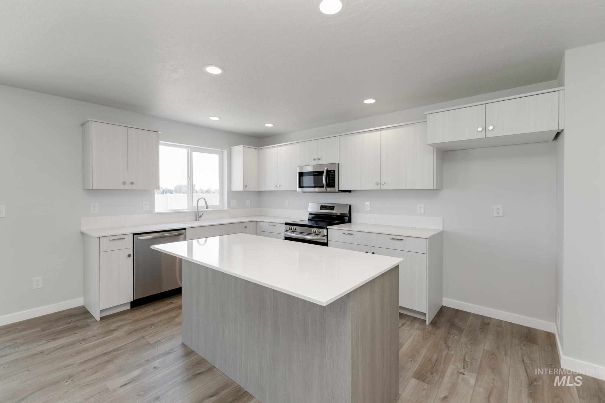 16366 Backfill Avenue Caldwell, ID 83607 - Photo 4 of 24 Kitchen with appliances with stainless steel finishes, a kitchen island, white cabinetry, recessed lighting, and light wood-style floors