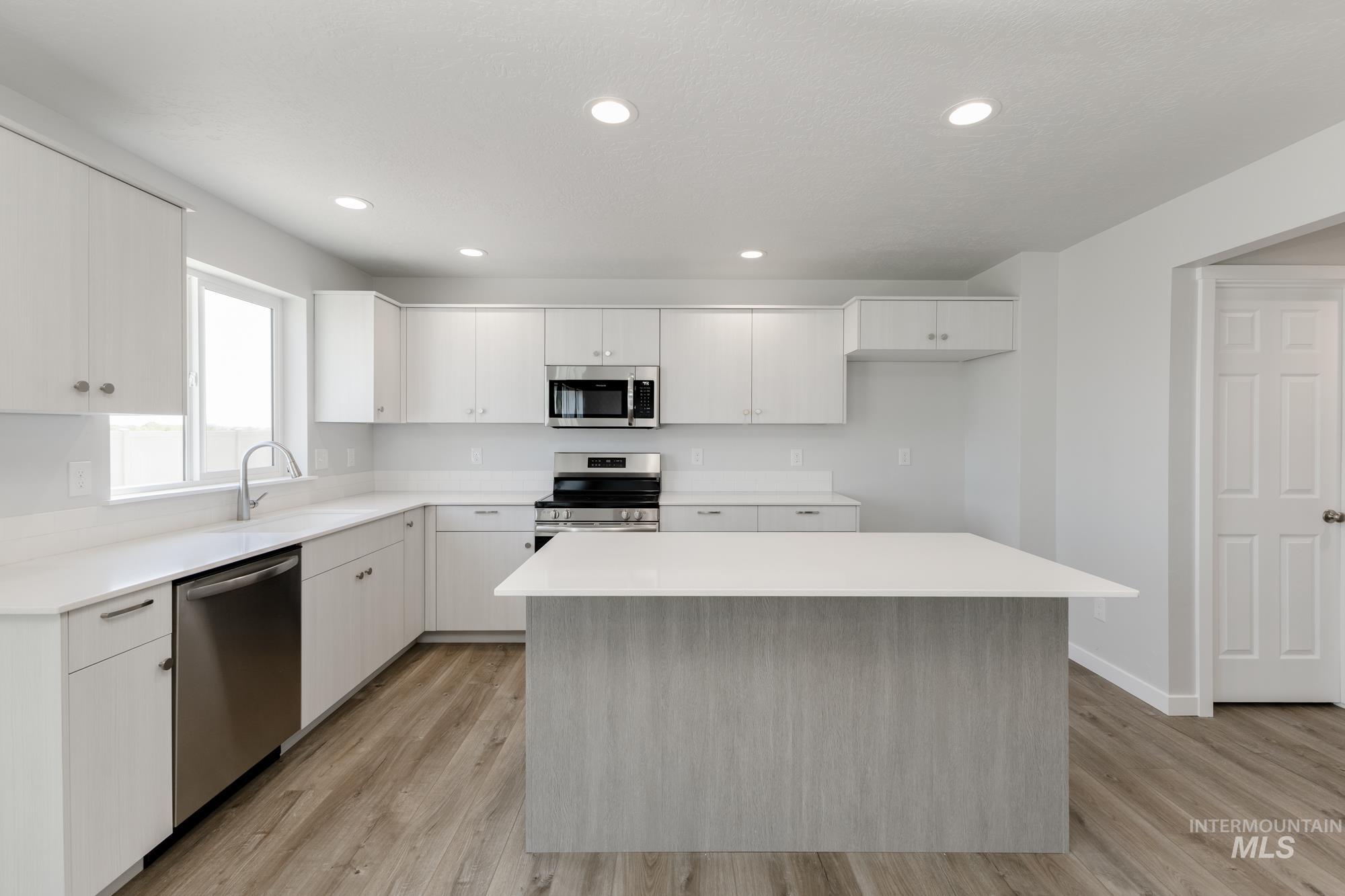 16366 Backfill Avenue Caldwell, ID 83607 - Photo 5 of 24 Kitchen featuring appliances with stainless steel finishes, white cabinetry, a center island, light wood-style flooring, and recessed lighting