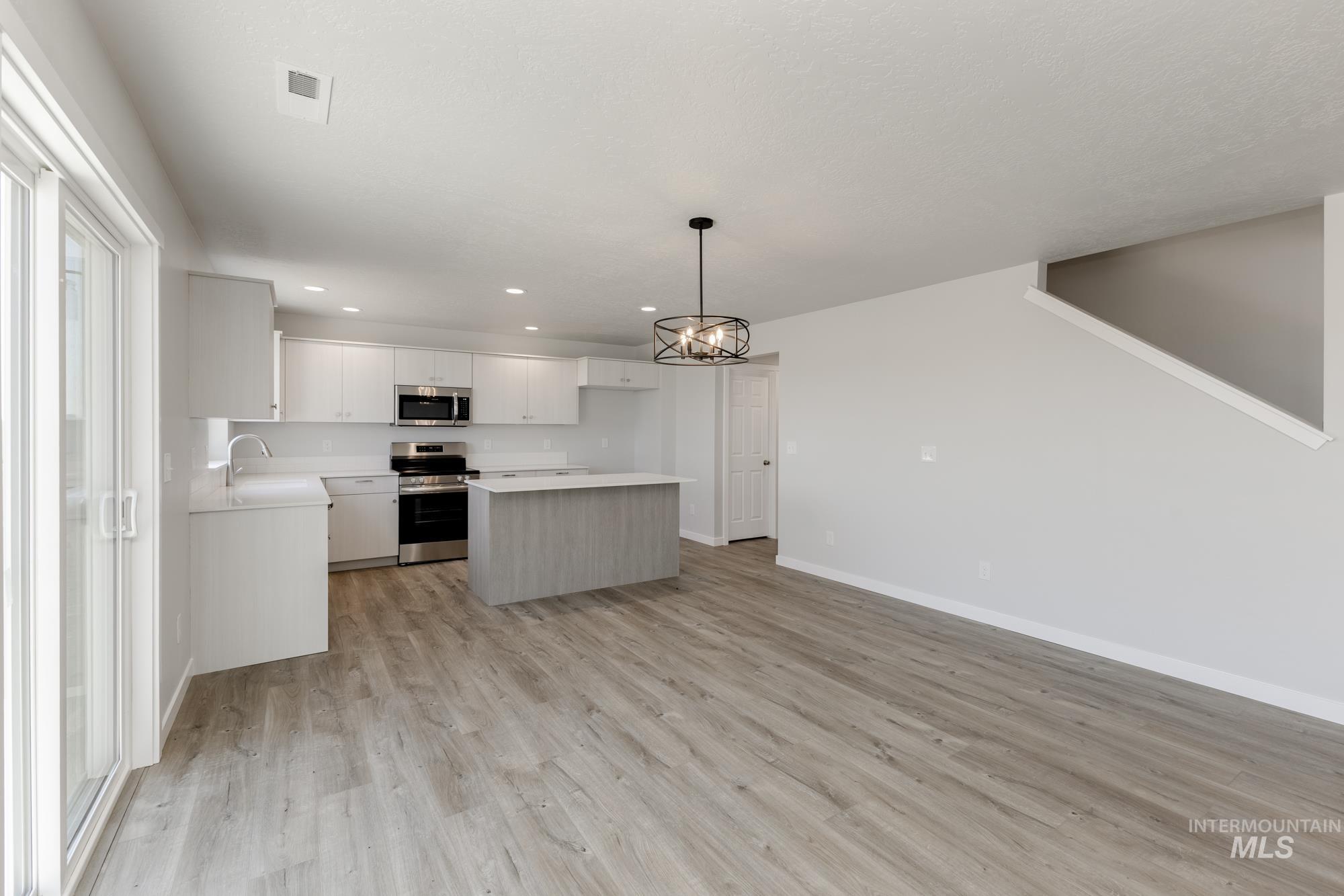16366 Backfill Avenue Caldwell, ID 83607 - Photo 7 of 24 Kitchen featuring light countertops, white cabinetry, pendant lighting, a kitchen island, and a chandelier