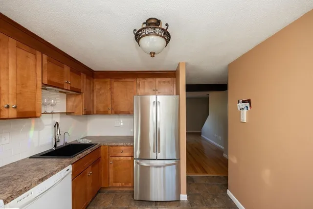 a kitchen with stainless steel appliances granite countertop a refrigerator a stove and a sink