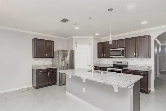 a kitchen with stainless steel appliances a sink a stove a microwave a sink a refrigerator and cabinets